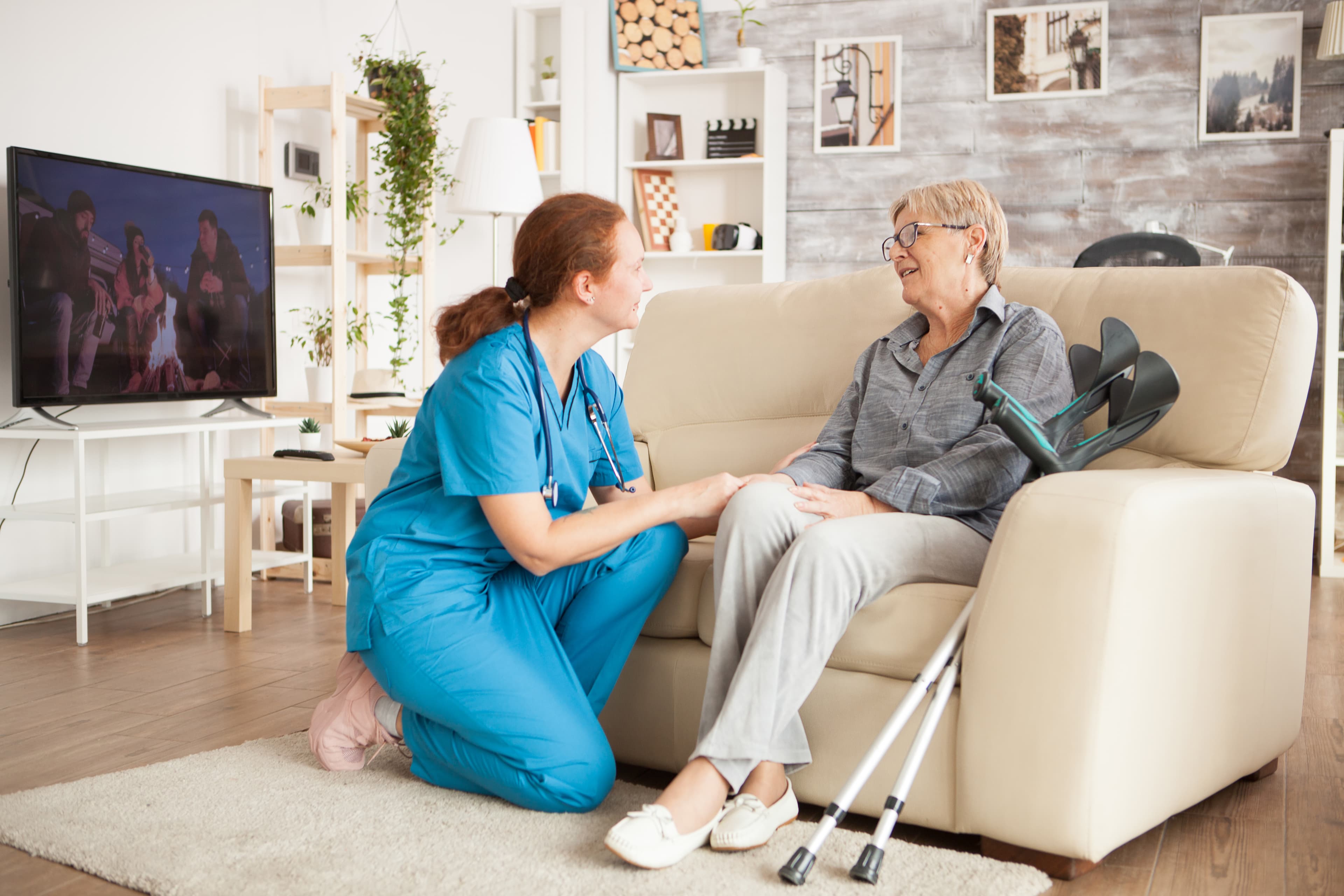 Nurse assisting an elderly patient walk at home